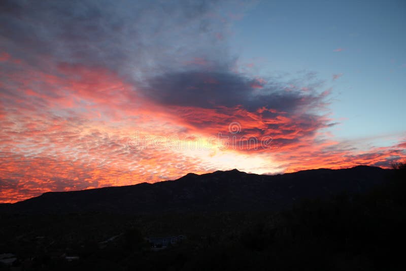 Hot pink and orange cotton candy dawn clouds over the mountains in Tucson Arizona