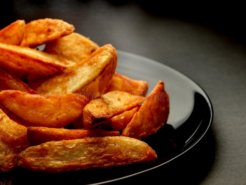 Hot spicy potato wedges on black plate. Crispy diet stock images, royalty-free photos and pictures