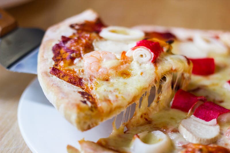 Hot seafood pizza slice with melting cheese on rustic wooden royalty free stock photos Hot seafood pizza slice with melting cheese on rustic wooden royalty free stock photos