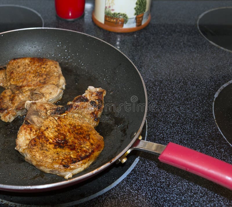 Skillet with pork chops on the stove top.