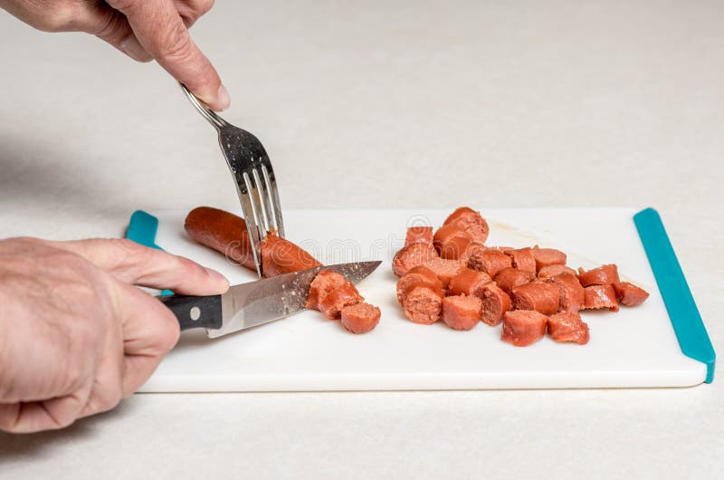 Hotdogs Sliced with Knife and Fork on a Cutting Board Stock Image
