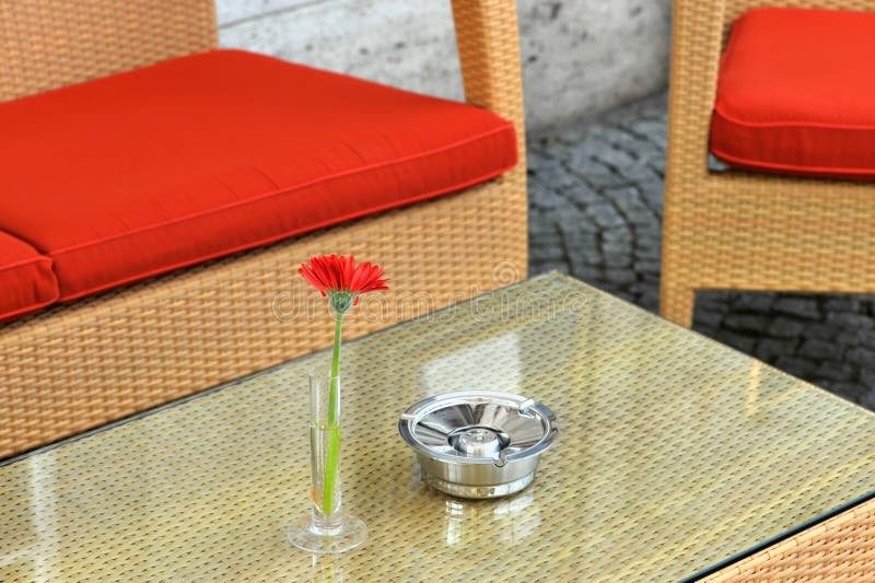 Hotel exterior with table, red chairs, red flower and ashtray. Hotel exterior with table, red chairs, red flower and ashtray