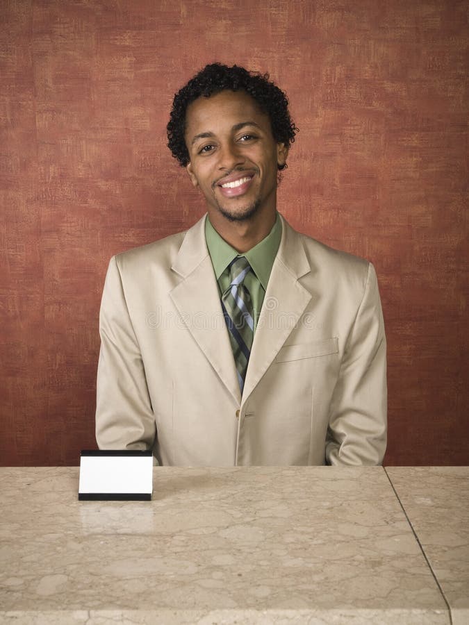 A hotel employee cheerfully welcomes guests. A hotel employee cheerfully welcomes guests.