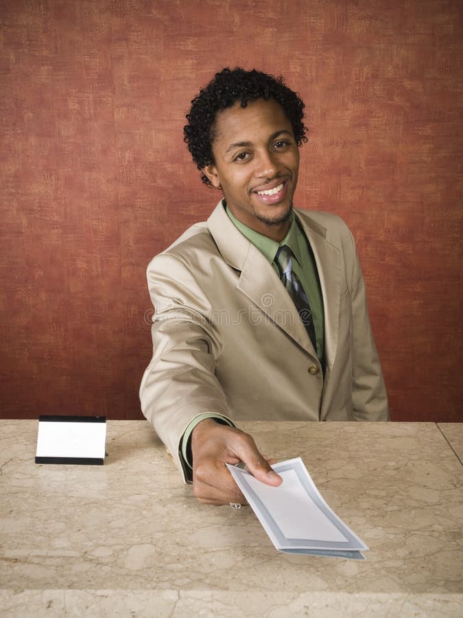 A hotel employee cheerfully welcomes guests. A hotel employee cheerfully welcomes guests.