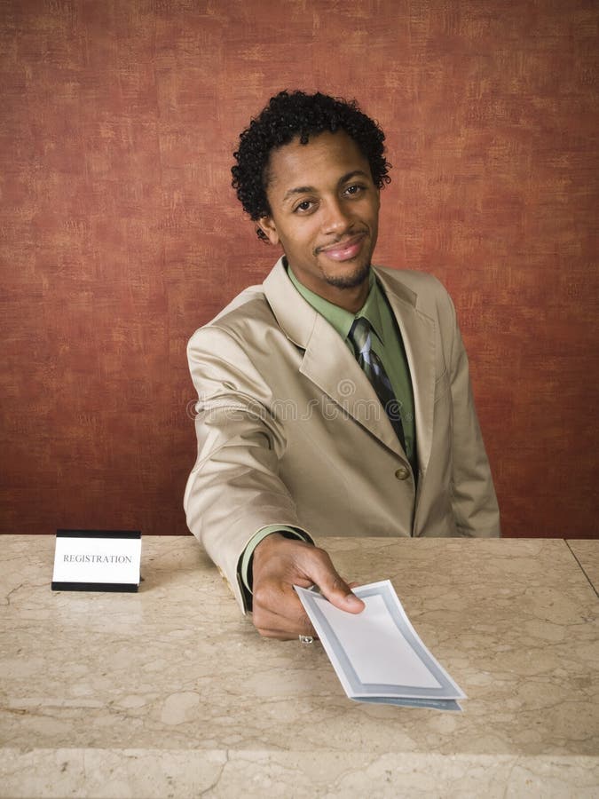A hotel employee cheerfully welcomes guests. A hotel employee cheerfully welcomes guests.