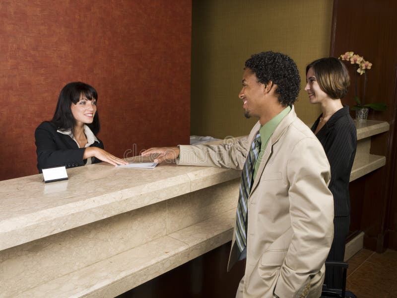 A hotel employee cheerfully welcomes guests. A hotel employee cheerfully welcomes guests.