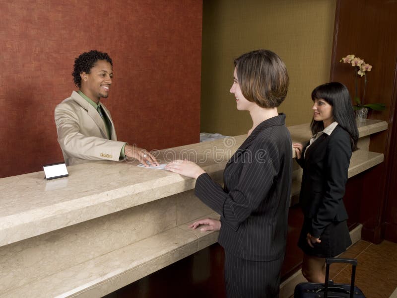 A hotel employee cheerfully welcomes guests. A hotel employee cheerfully welcomes guests.
