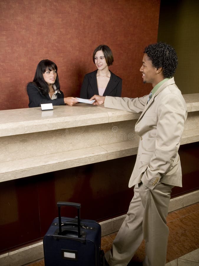 Hotel employees cheerfully welcome a guest. Hotel employees cheerfully welcome a guest.