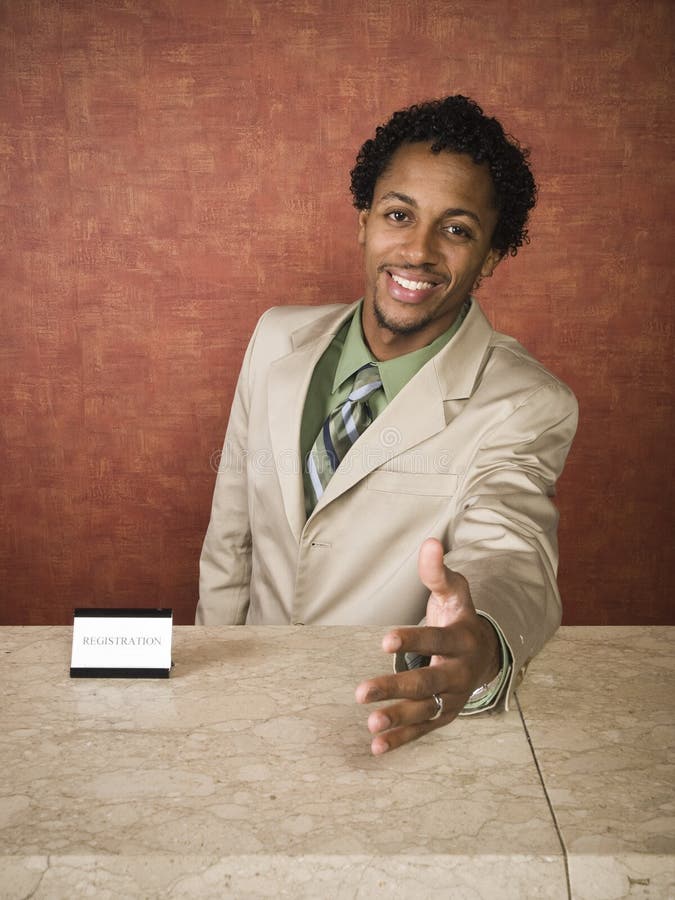 A hotel employee cheerfully welcomes guests. A hotel employee cheerfully welcomes guests.