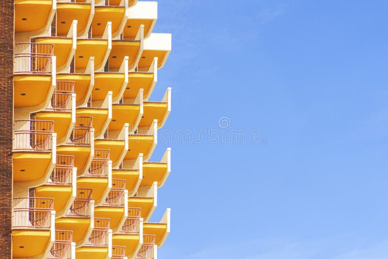 Hotel room balconies in modern building. Geometric pattern of balcony against blue sky background stock image