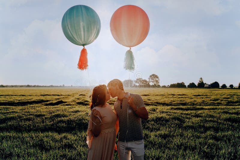 Houdend van paar die zich op het gebied met helium gekleurde ballen bevinden royalty-vrije stock fotografie Houdend van paar die zich op het gebied met helium gekleurde ballen bevinden royalty-vrije stock fotografie