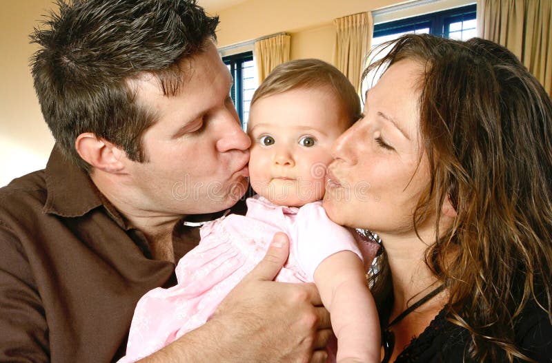 Houdende van moeder en vader die hun babymeisje kussen stock afbeelding Houdende van moeder en vader die hun babymeisje kussen stock afbeelding