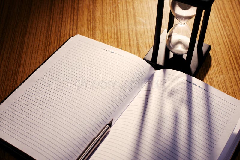 Hourglass Casting Shadow on Notebook with Pen