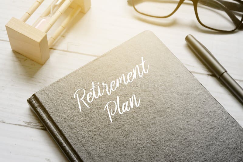 Hourglass,eyeglass,pen and notebook written with RETIREMENT PLAN on white wooden background with sun flare