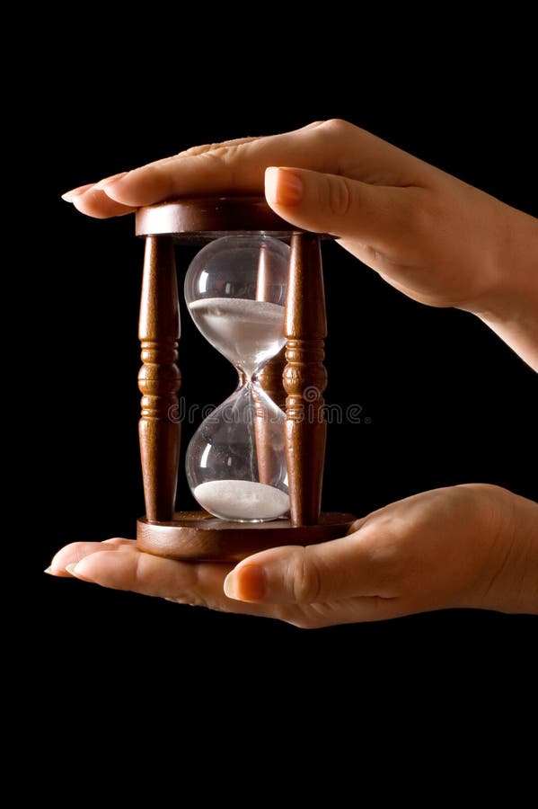 Hourglass in hands on a black