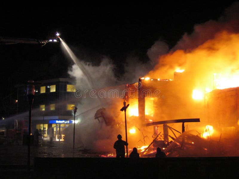 Building in full flaming inferno, and the firefighters fighting to get control of the flames. Building in full flaming inferno, and the firefighters fighting to get control of the flames