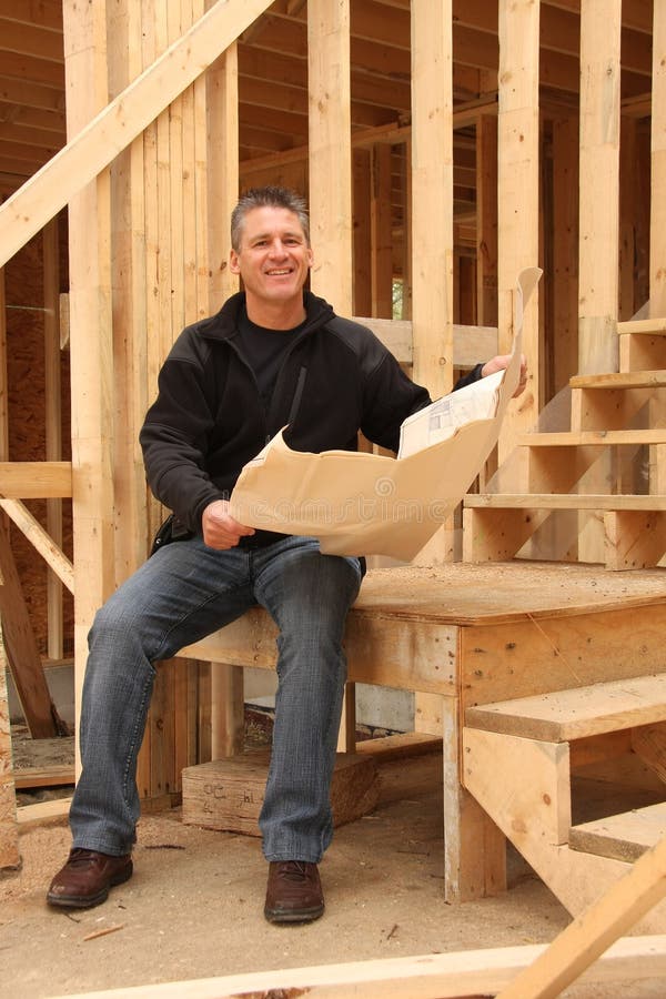 Builder with blue prints in a house under construction. Builder with blue prints in a house under construction.