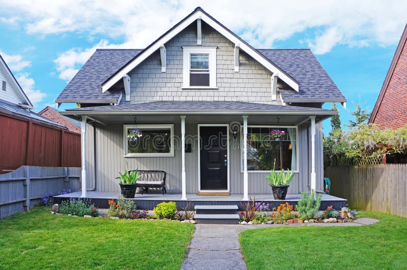 Small old house with entrance porch decorated with antique bench. Front yard has lawn and flower beds. Small old house with entrance porch decorated with antique bench. Front yard has lawn and flower beds