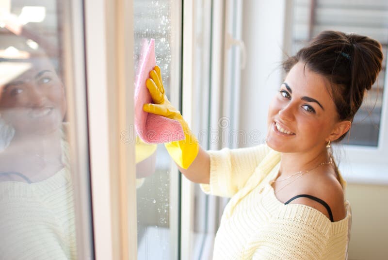 Mujer bonita lavar ventanas en guantes.