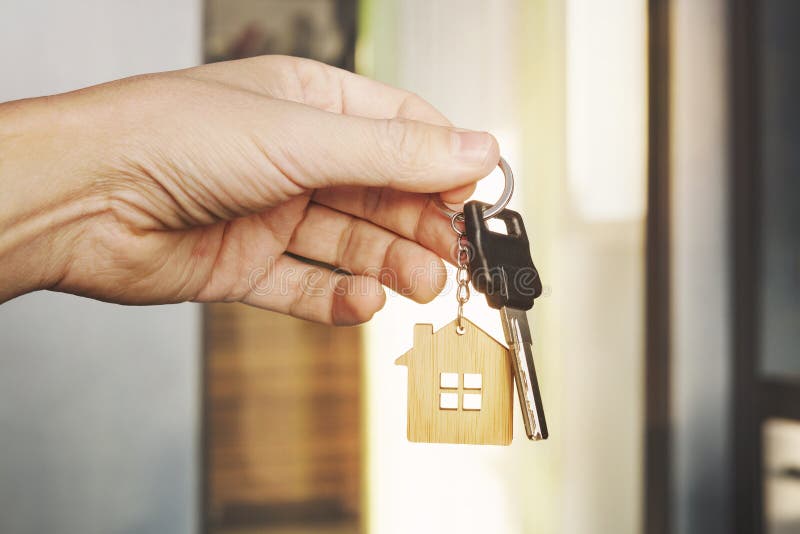 House key in male hand at apartment background. house key ring. Concept of moving in new living apartment. Symbol of purchasing royalty free stock photography House key in male hand at apartment background. house key ring. Concept of moving in new living apartment. Symbol of purchasing royalty free stock photography