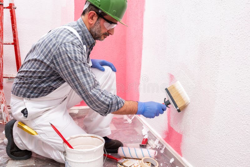 House Painter Worker at Work in the Construction Site. Building Stock