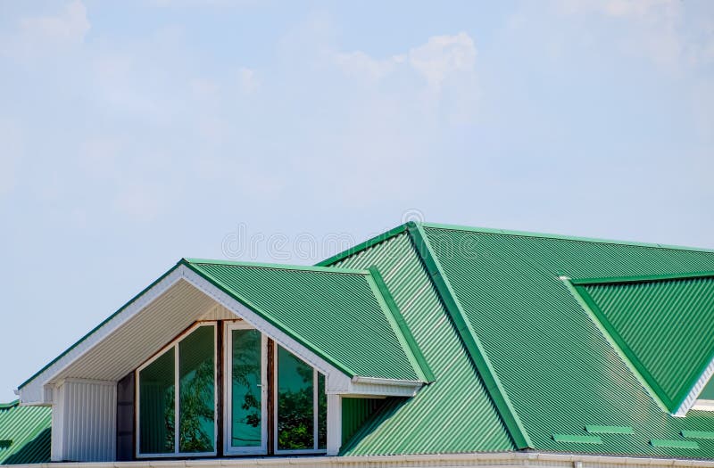 The house with plastic windows and a green roof of corrugated sheet. Green roof of corrugated metal profile and plastic windows