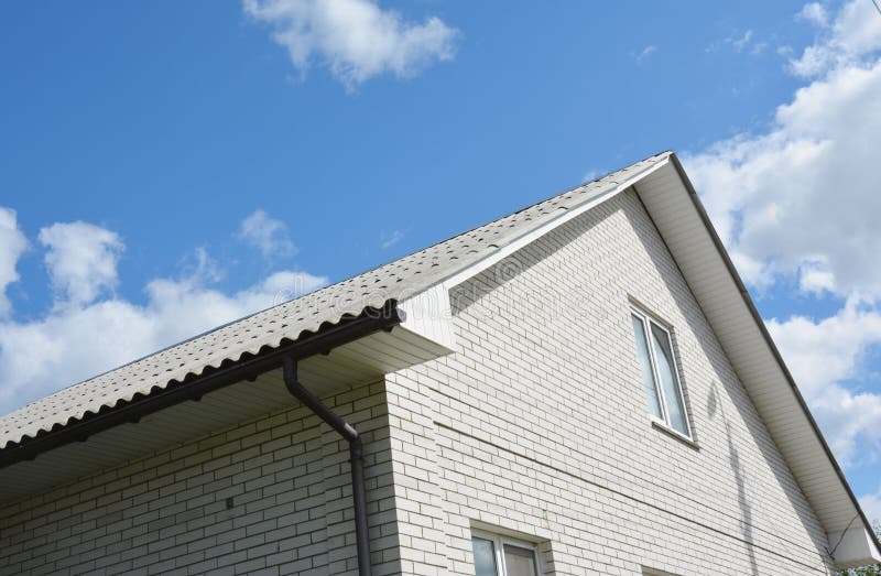 House Rooftop with Asbestos Roof, White Bricks and Rain Gutter Stock