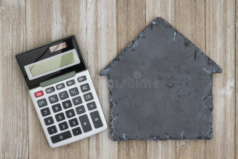 House Shaped Chalkboard with Calculator on Weathered Wood Stock Photo
