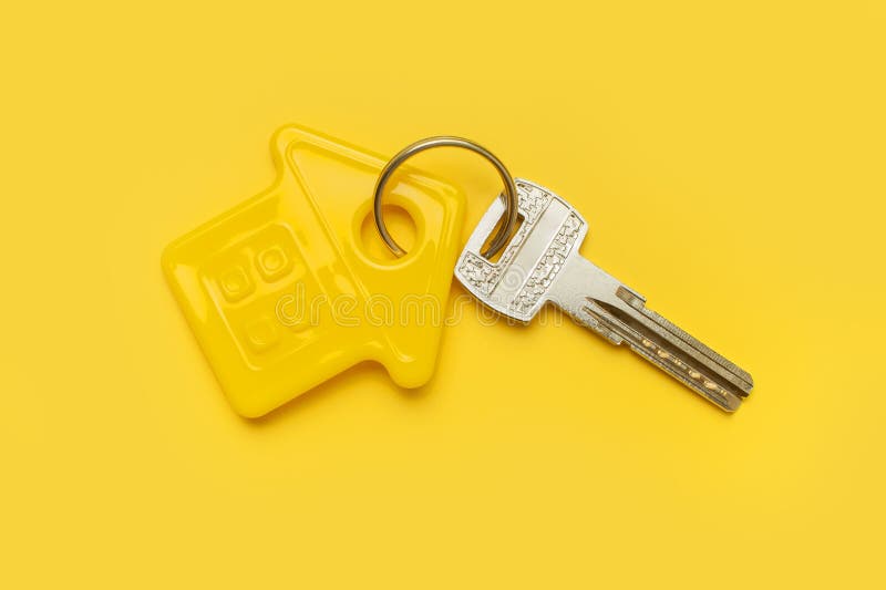 House symbol and metal keys on yellow background flat lay top view copy space. House door keys. Concept of buying home, apartment stock photo