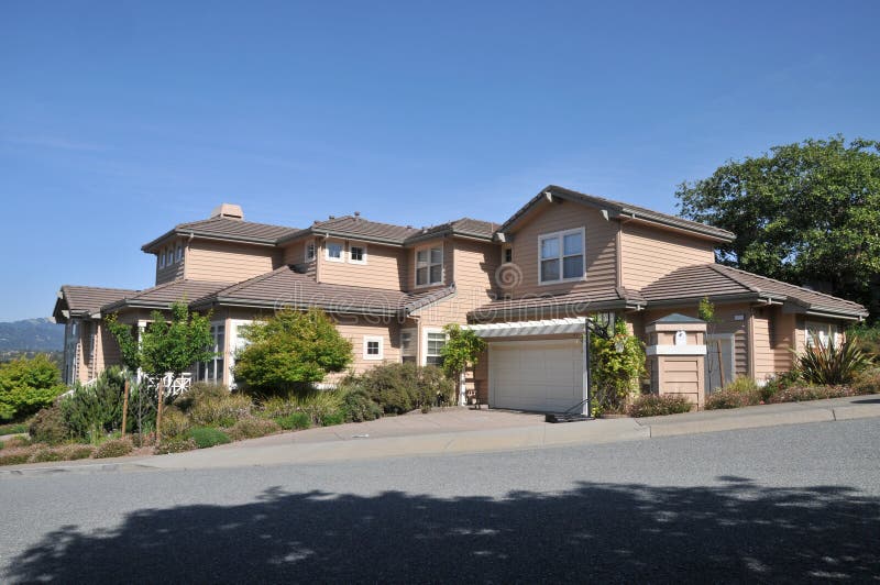 House with two stories on a hill off street.