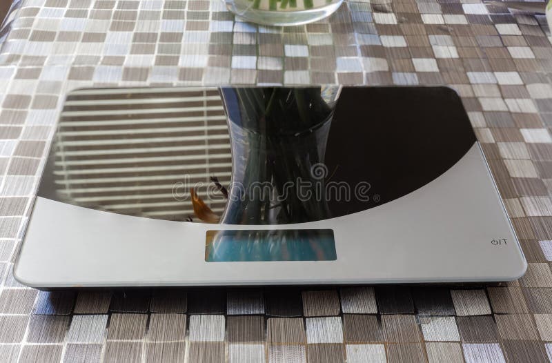 Household Digital Kitchen Scale on Table Covered with Oilcloth Stock
