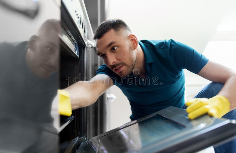 Man with rag cleaning inside oven at home kitchen