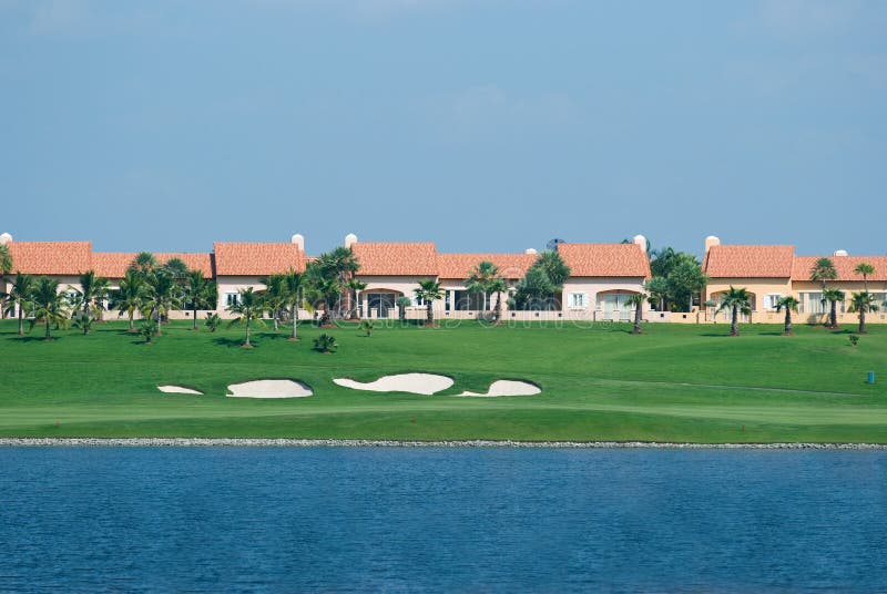 Fairway at a golf course with bungalows in the background and lake in the foreground. Fairway at a golf course with bungalows in the background and lake in the foreground.