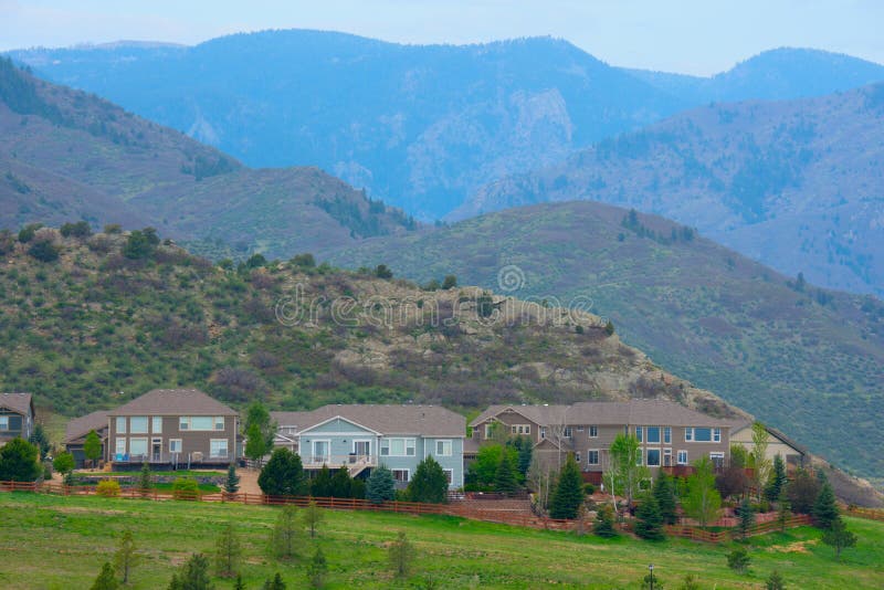 Houses on a mountainside with mountain peaks and green grass