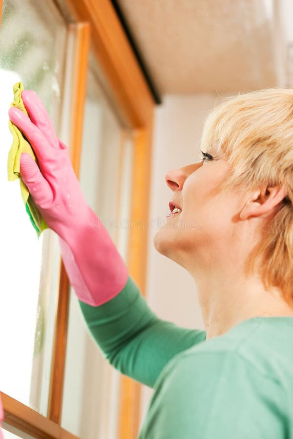 Housewife cleaning her windows in rubber gloves stock photos