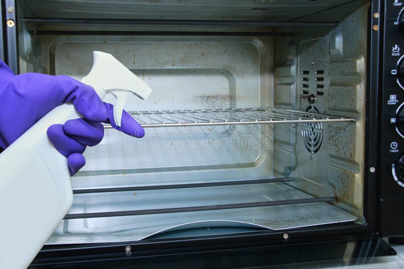 Housewife. Dirty oven. Hand blue protective glove with cleaning agent stock photo Housewife. Dirty oven. Hand blue protective glove with cleaning agent stock photo