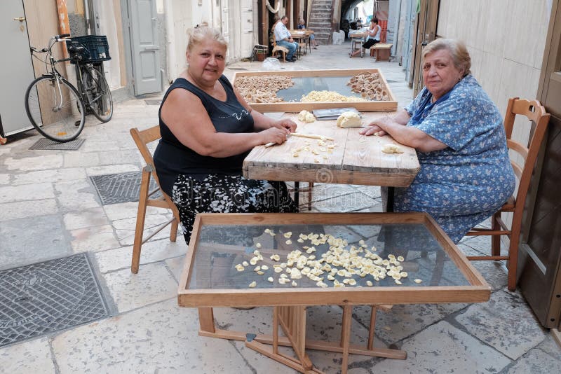 Housewifes que faz a massa fresca em Bari velho, Itália