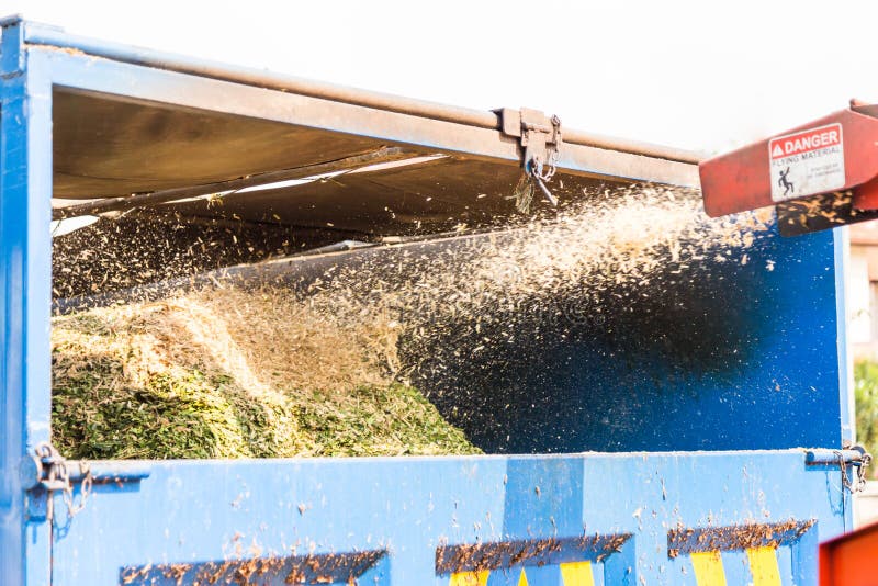 Houten chipper machine die het verscheurde hout vrijgeven van een vrachtwagen stock fotografie Houten chipper machine die het verscheurde hout vrijgeven van een vrachtwagen stock fotografie