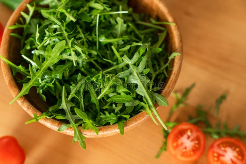 Houten Kom van verse groene, natuurlijke arugula met kersentomaten op een houten achtergrond royalty-vrije stock afbeeldingen Houten Kom van verse groene, natuurlijke arugula met kersentomaten op een houten achtergrond royalty-vrije stock afbeeldingen