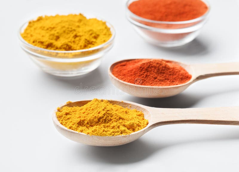 Houten lepels en kommen met paprika en kurkumapoeder op wit stock afbeelding Houten lepels en kommen met paprika en kurkumapoeder op wit stock afbeelding