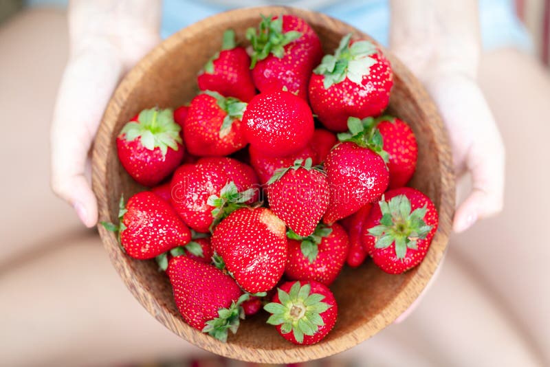 Houten plaat met aardbeien in meisjeshand op lichte achtergrond stock afbeelding Houten plaat met aardbeien in meisjeshand op lichte achtergrond stock afbeelding