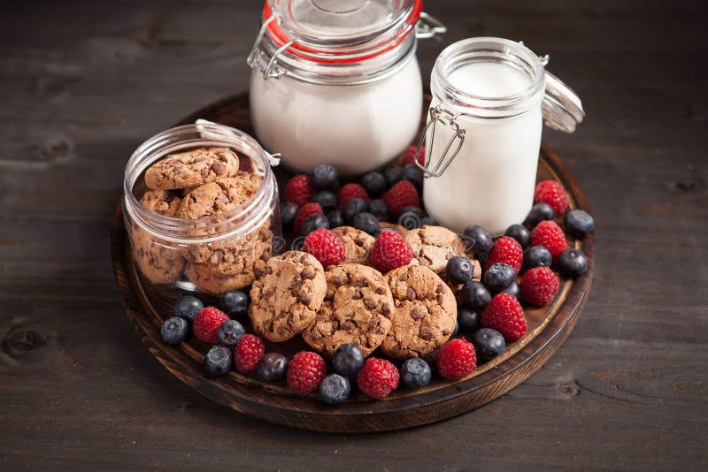 Houten plaathoogtepunt van delicios en smakelijke koekjes naast verse bluebarries stock foto Houten plaathoogtepunt van delicios en smakelijke koekjes naast verse bluebarries stock foto