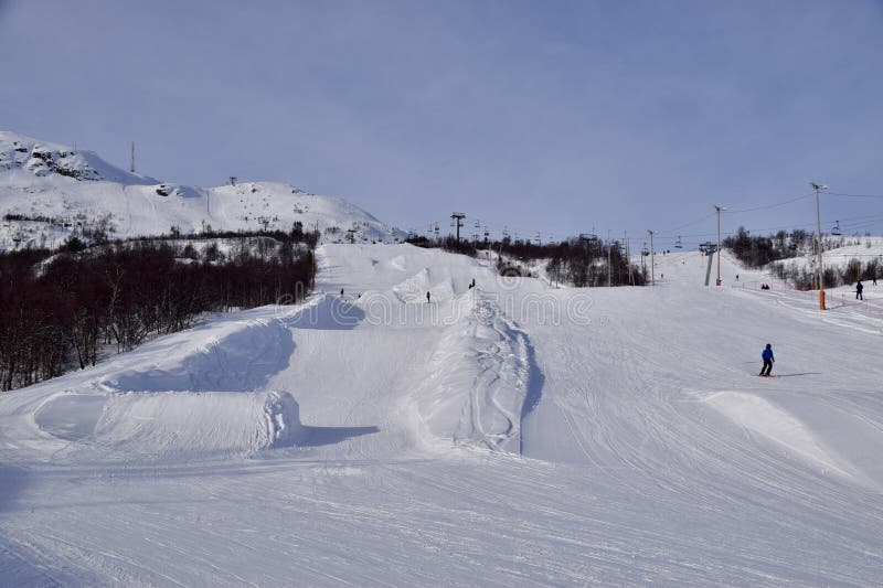 Hovden Alpinsenter, ski resort, Norway, with ski slopes. Mountain with snow and trees, people skiing and snowboarding. B.