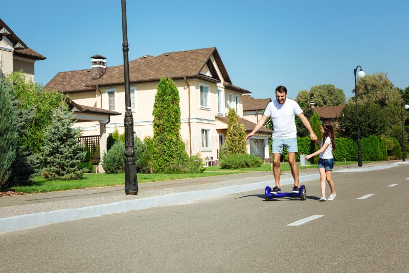 Hoverboard feliz del montar a caballo del padre así como hija fotografía de archivo Hoverboard feliz del montar a caballo del padre así como hija fotografía de archivo