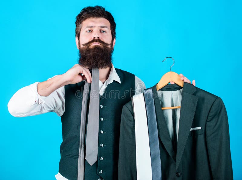 How about this tie. Brutal hipster holding colorful tie collection and suit jacket. Bearded man matching neck tie color to formal coat. Choosing a perfect tie.