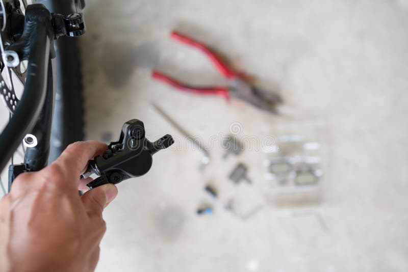 How to maintenance a mtb hydraulic disc brake caliper : Repairman holding a Hydraulic rear disc brake caliper on a mountain bike.