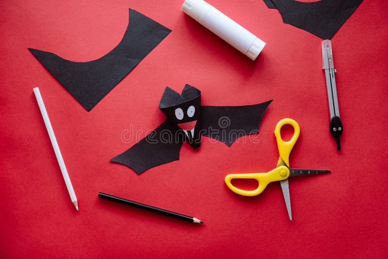 Preparing for Halloween. Teenage kid hands cutting black paper bat