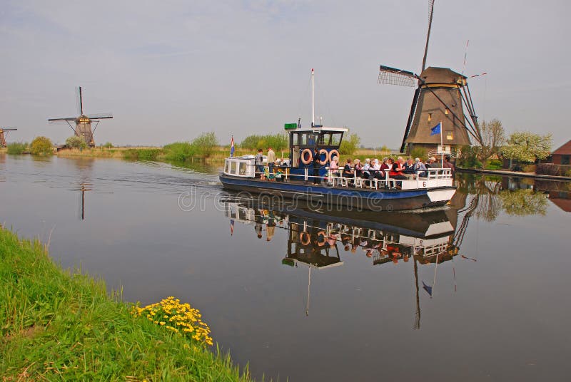 Tourists enjoy local boat tour on a Dutch river stream at Kinderdijk with view of Windmills, Netherlands