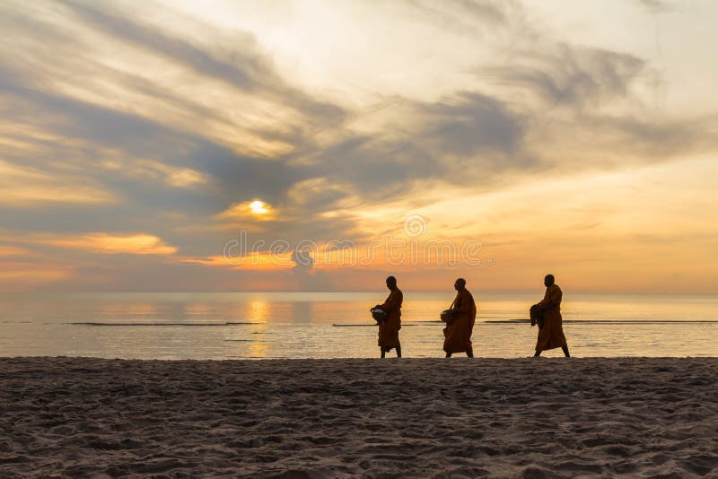 Three monks are walking on beach