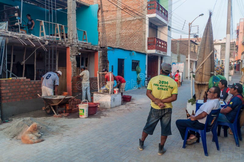 HUANCHACO, PERU - 6. JUNI 2015: Gruppe des lokalen Mannes ist, aufpassend sitzend und Bauarbeiter lizenzfreie stockbilder HUANCHACO, PERU - 6. JUNI 2015: Gruppe des lokalen Mannes ist, aufpassend sitzend und Bauarbeiter lizenzfreie stockbilder